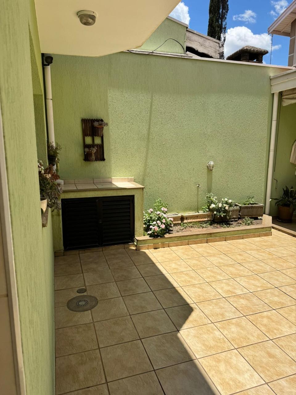 Área externa antes da reforma, com parede pintada de verde-limão e piso cerâmico amarelado.