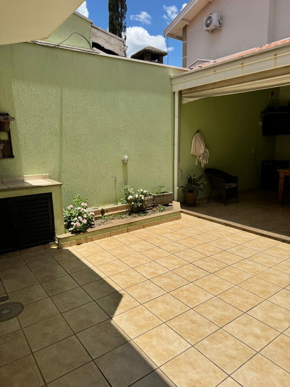Quintal antes da reforma, com parede verde, canteiro estreito e piso cerâmico amarelado.