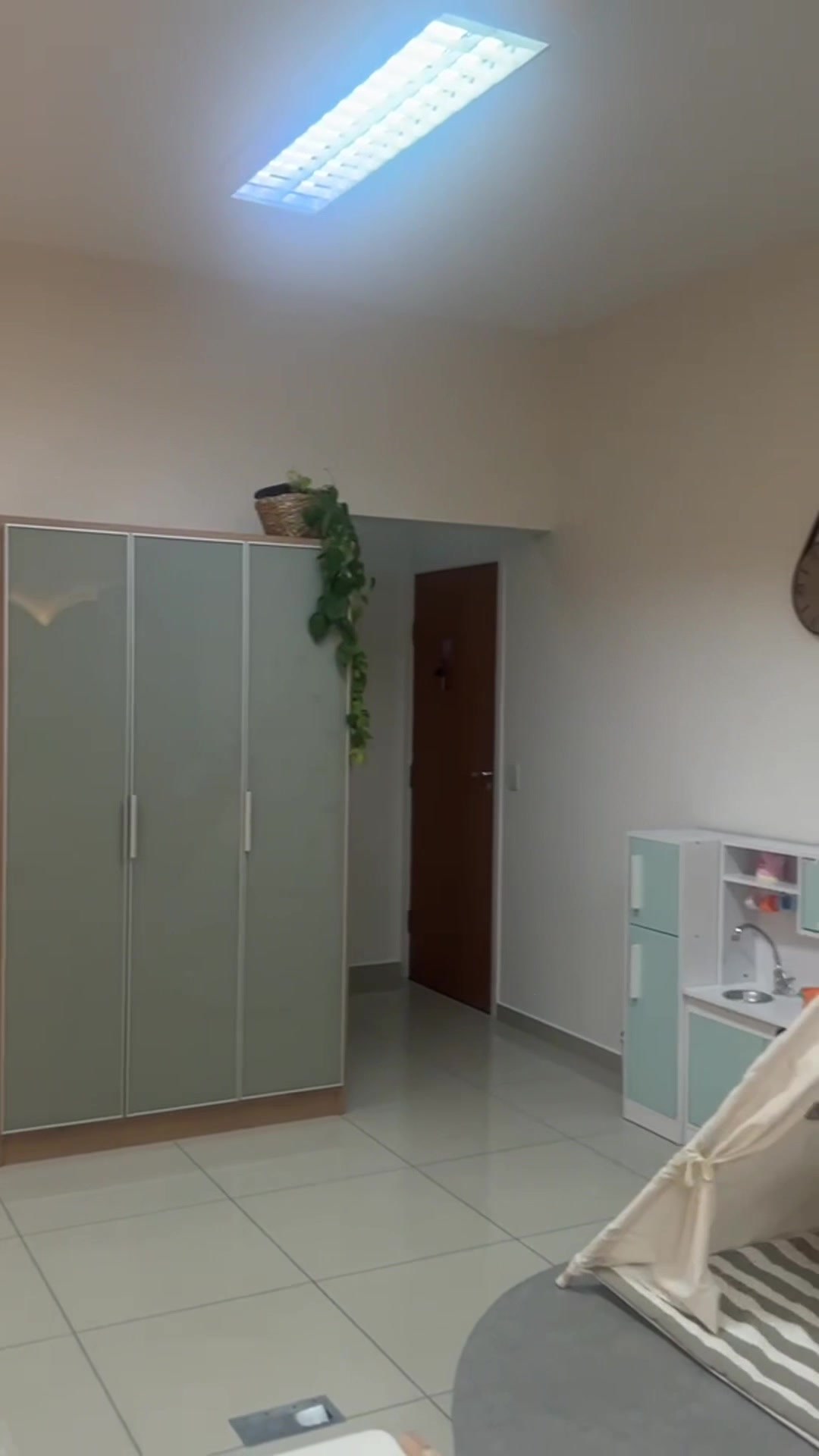 Canto de brincar com armários em verde-sálvia, cozinha de brinquedo e a cabana de tecido ao fundo