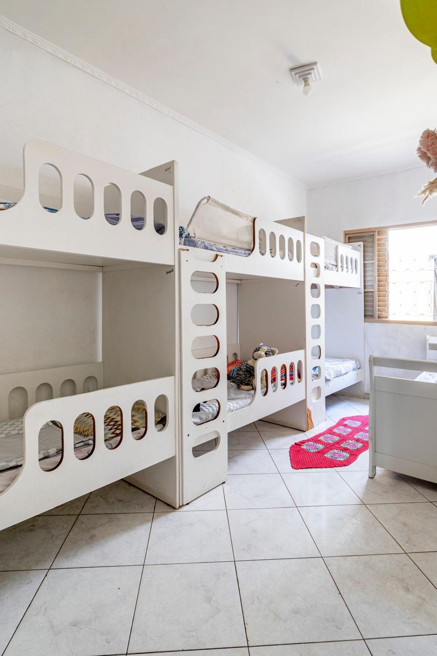 Dormitório infantil com beliches brancos antes da pintura da parede, ainda sem o mural e a faixa de cor.